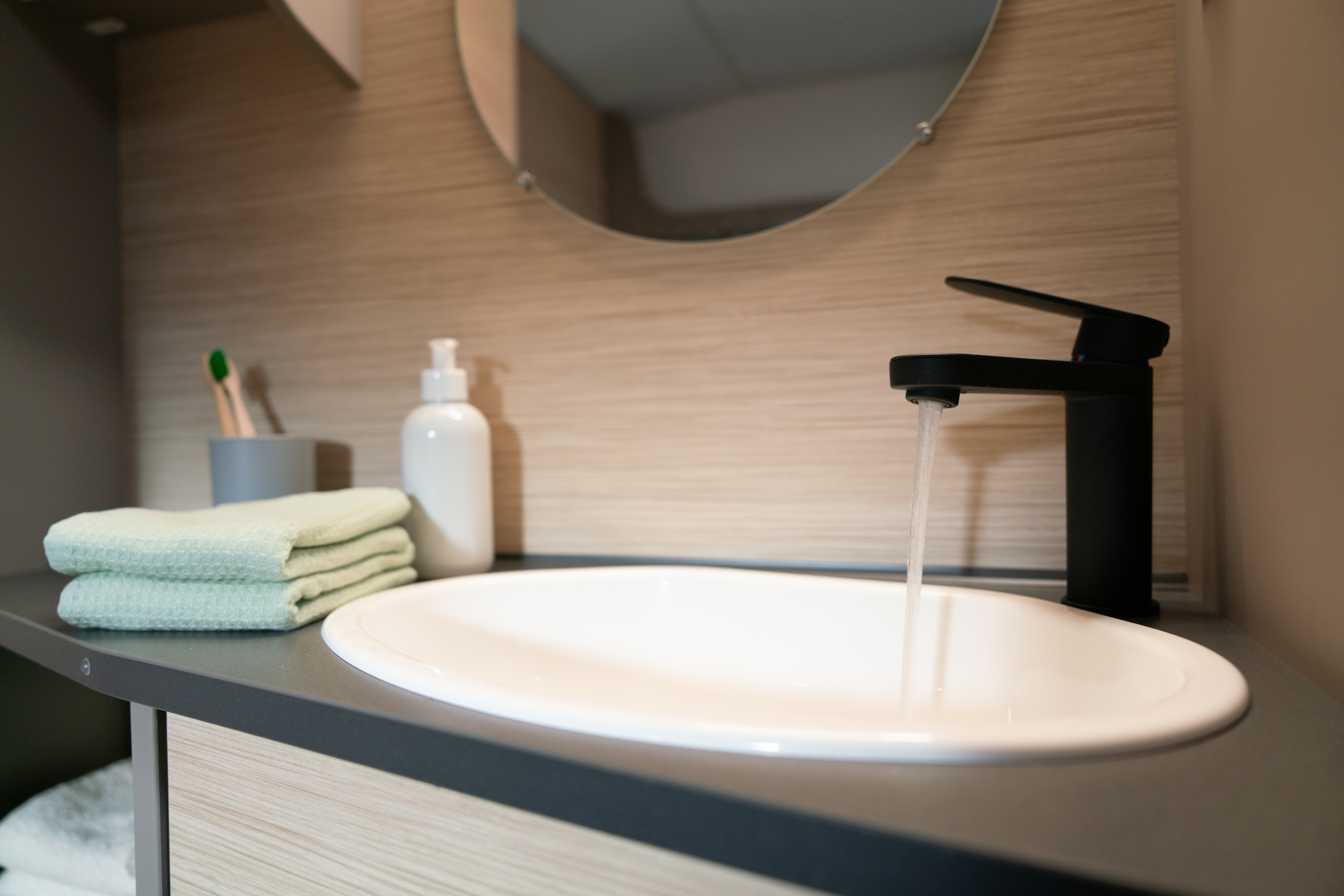 weißes ovales Waschbecken mit schwarzem Designer-Wasserhahn für kleine Wohnwagen mit WC